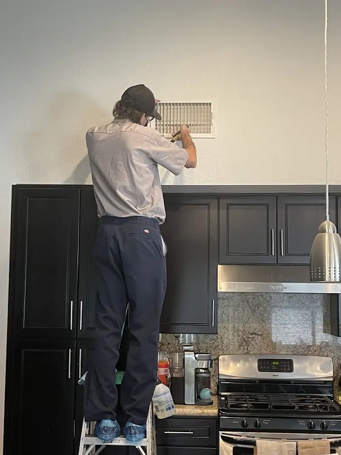 Technician inspecting an air vent during HVAC service in Sebastian